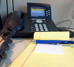 desk at an office with a phone and note pad
